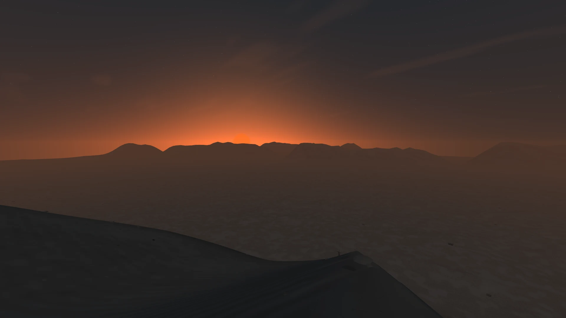 Sunset across a desert basin, with mountain ranges on the horizon.